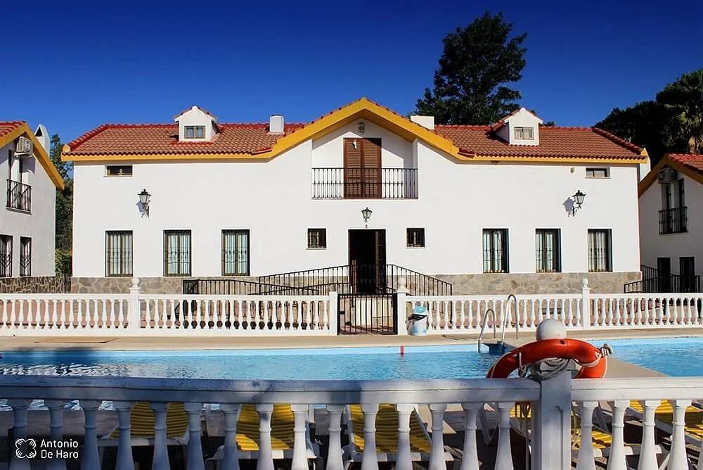 Casa rural blanca con tejado ámbar y piscina en el Complejo Los Pinos